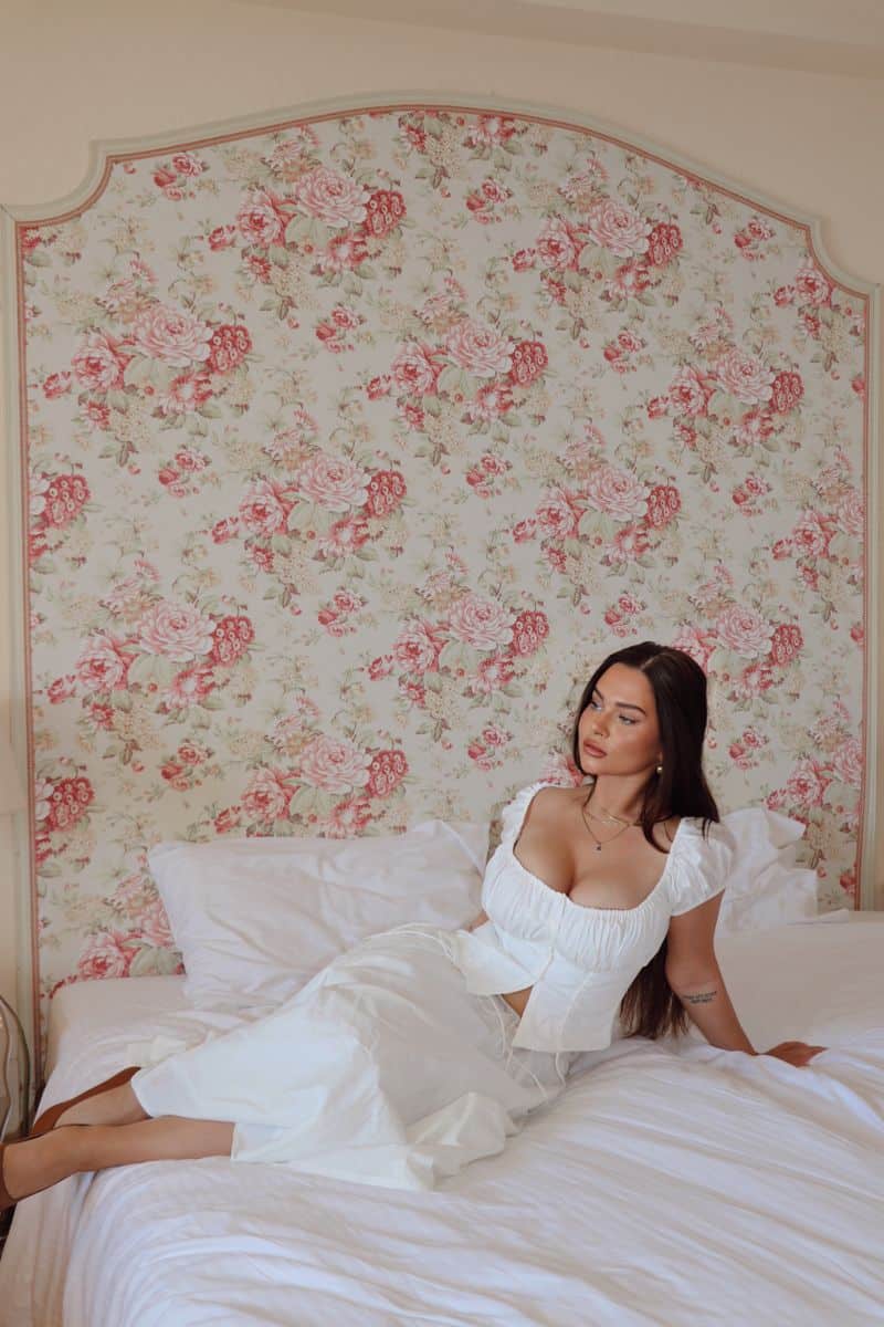 Sun-kissed beach lover call girl posing by window in resort hotel